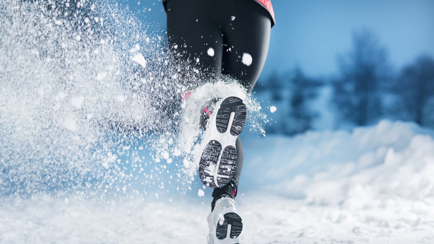 Eine Frau läuft im Winter mit Laufschuhe im Schnee