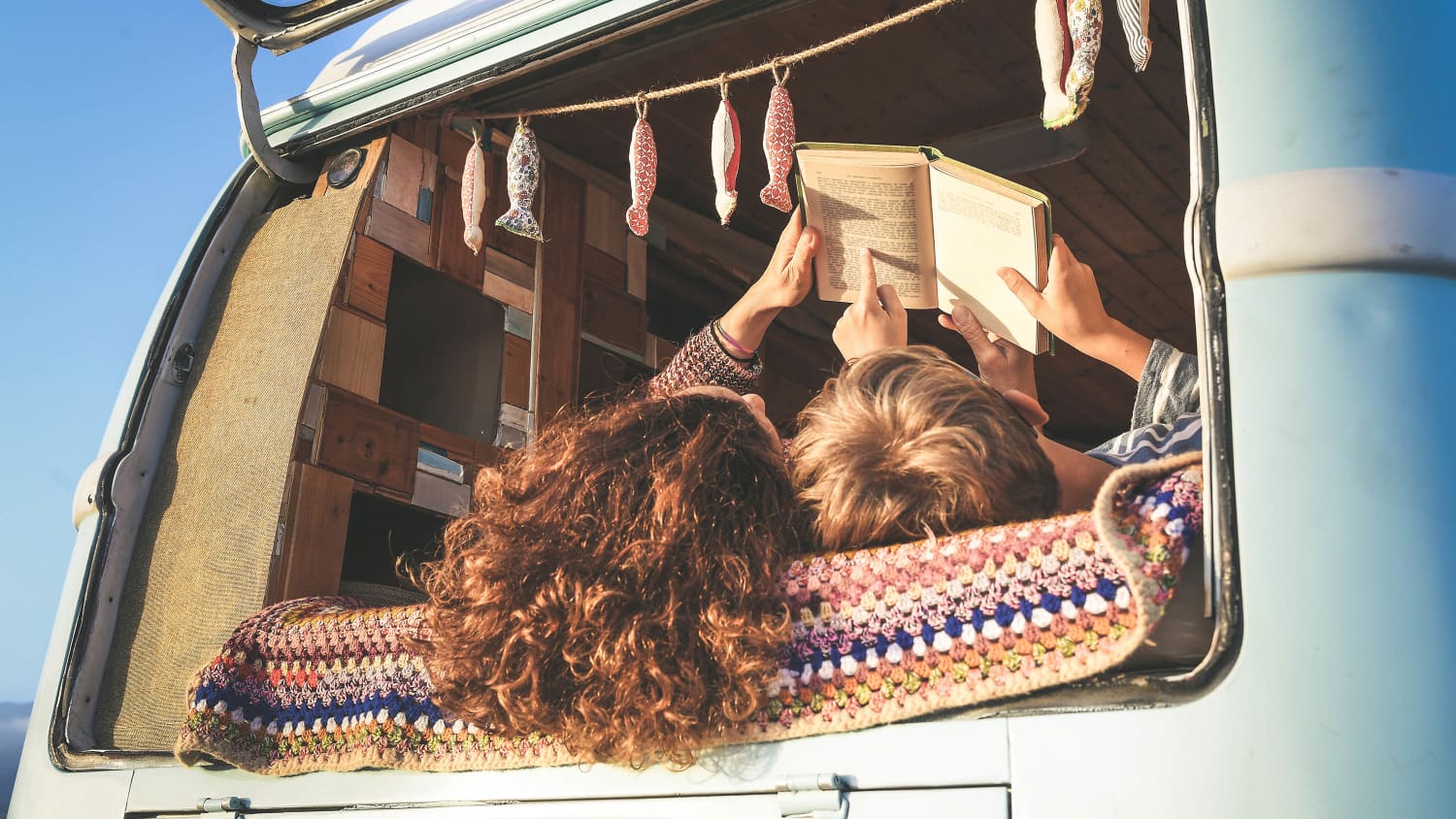 Lebensinspirationskonzept mit Hippie-Leuten auf Minivan, die zusammen ein Buch lesen
