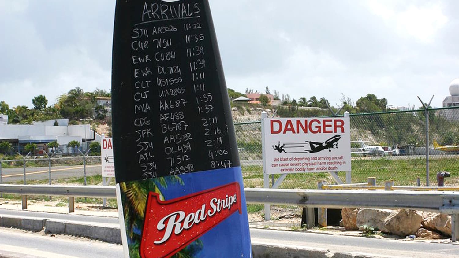 Ein Surfboard als Tafel mit den Ankunftszeiten der Flüge vor der Maho Beach Bar auf St. Martin