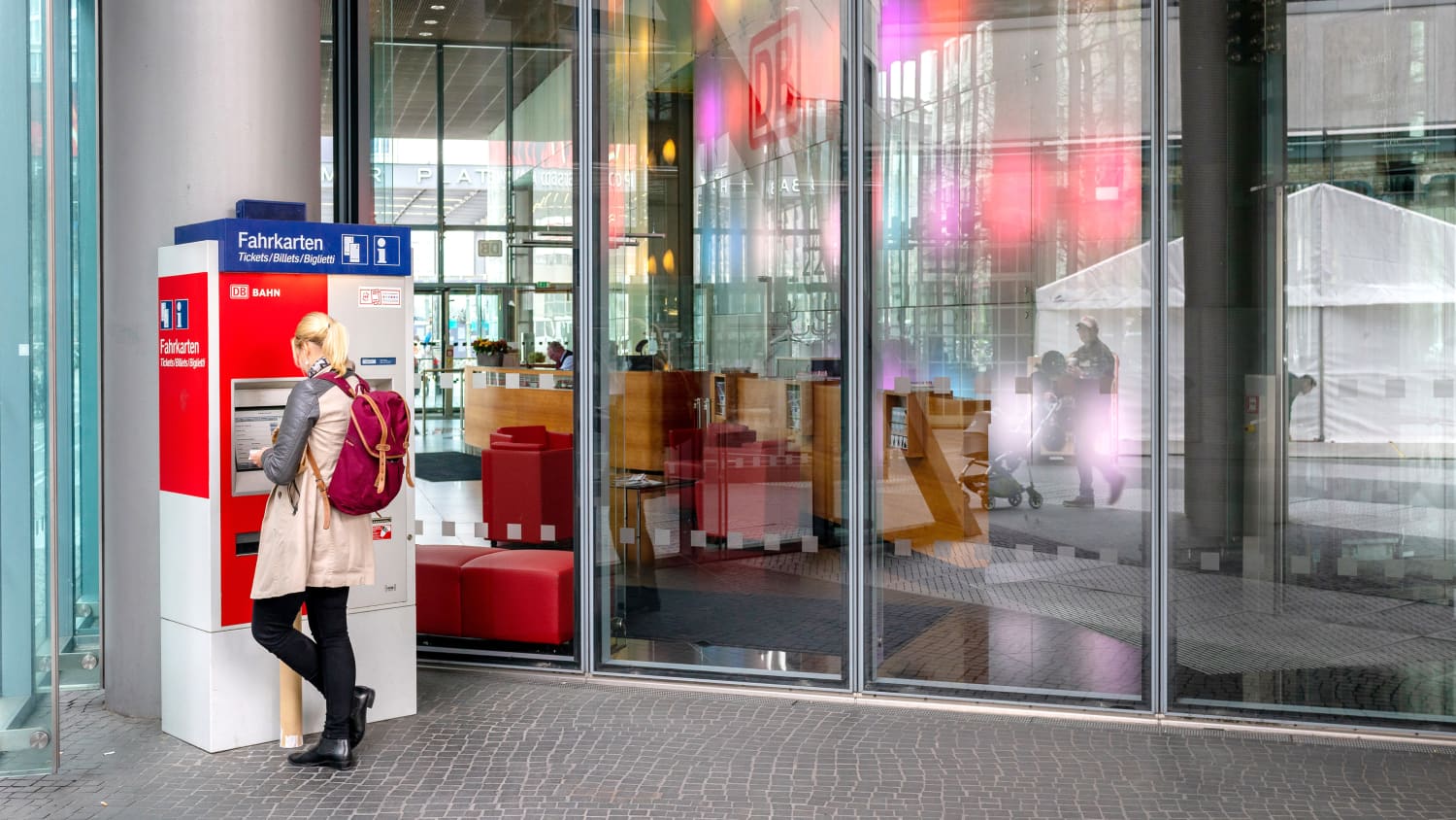 Frau kauft sich an einem Fahrkartenautomat ein Ticket