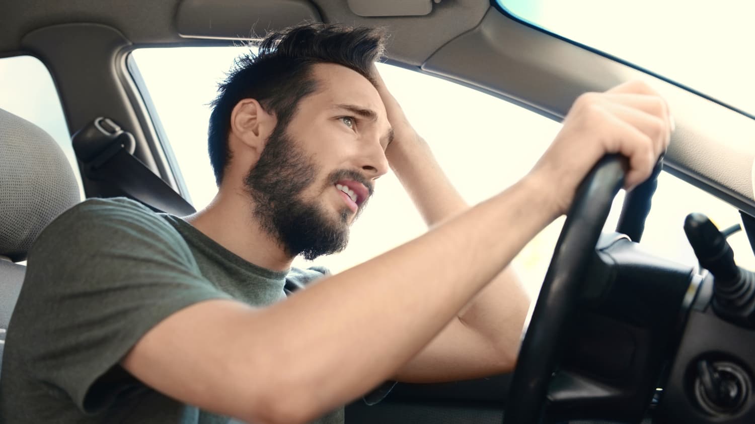 Ein junger Mann steht mit dem Auto im Stau und rauft sich die Haare