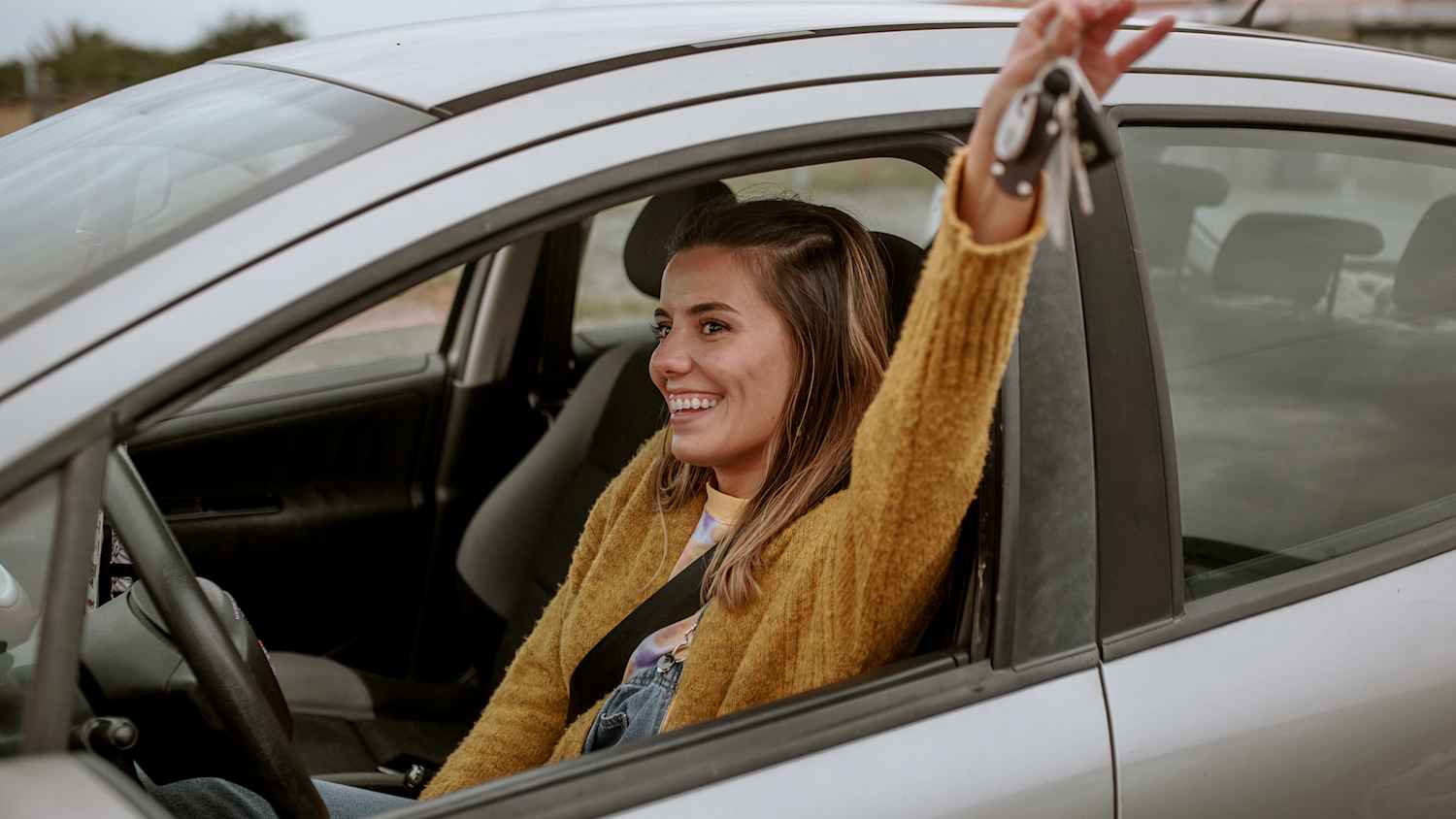 Eine junge Frau mit einem glücklichen Gesichtsausdruck hält ihre neuen Autoschlüssel in der Hand