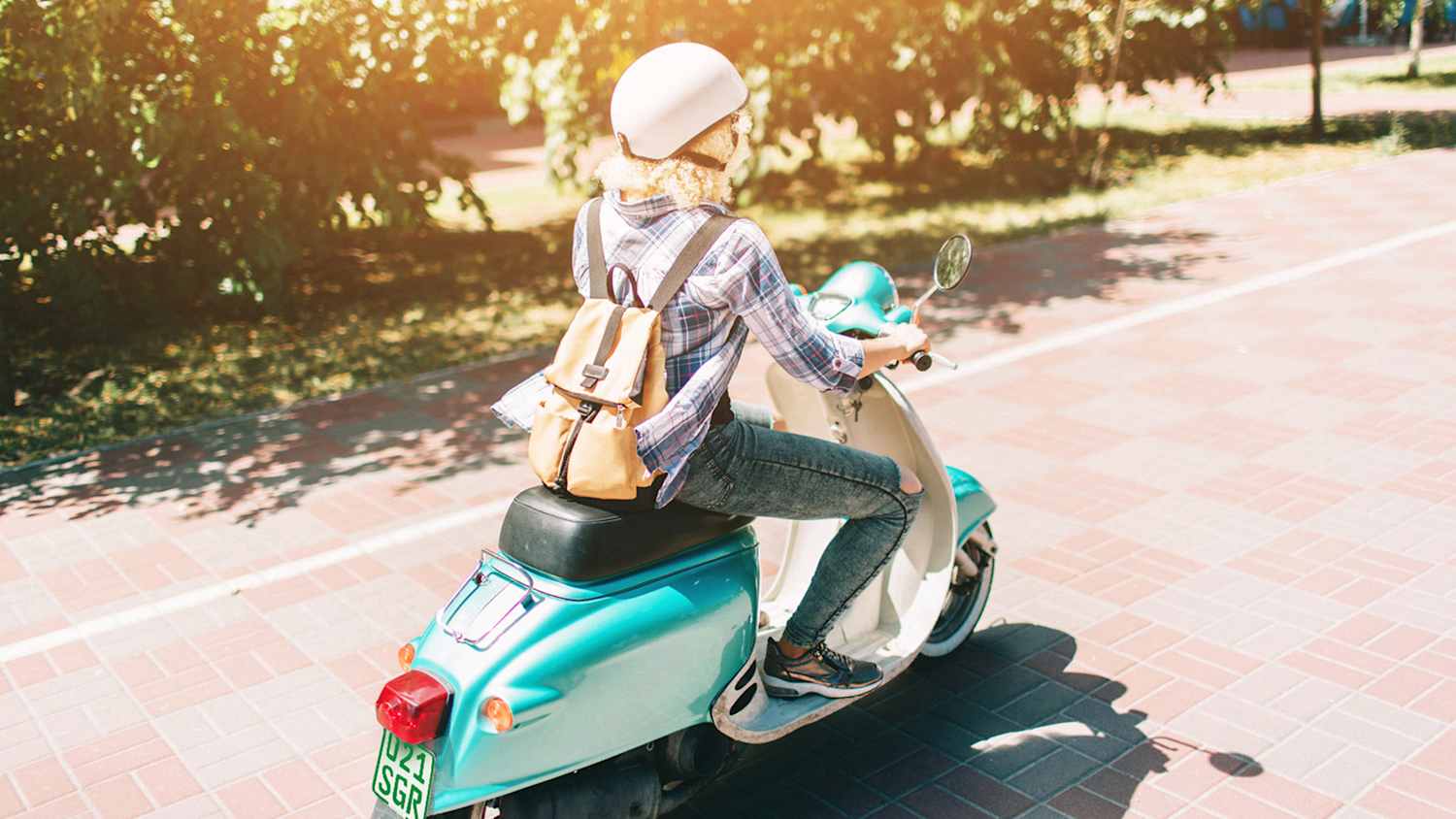 Eine Frau auf einer Vespa fährt auf einer Landstraße