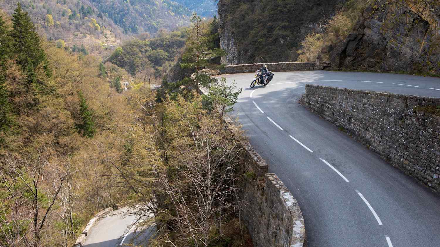 Kurvige Bergstraße am Col de Turini, umgeben von Felsen und Wald – ideal für Motorradtouren.