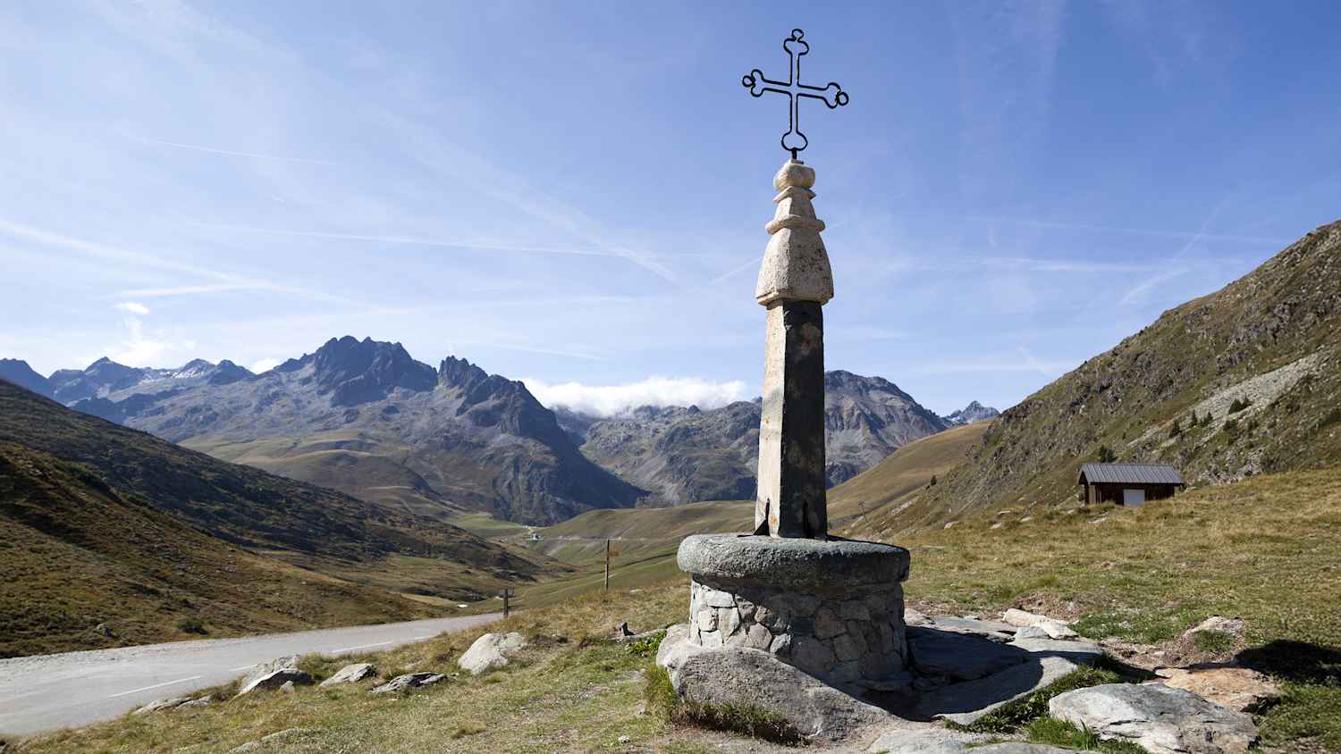 Kreuz am Col de la Croix de Fer mit malerischer Alpenlandschaft im Hintergrund.