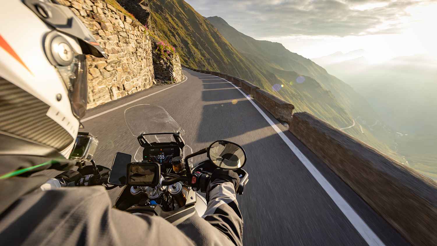 Motorradfahren in den italienischen Alpen bei Sonnenaufgang, Blick vom Lenker, dramatischer Himmel. Reisen und Freiheit, Aktivitäten im Freien