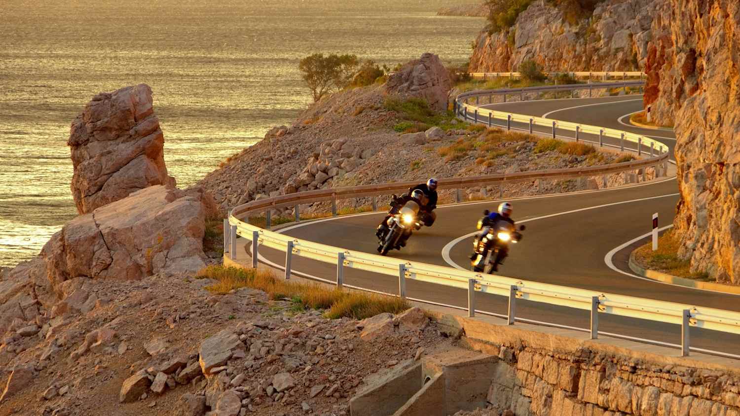 Motorradfahrer bei Sonnenunteragang auf der Küstenstraße in Kroatien
