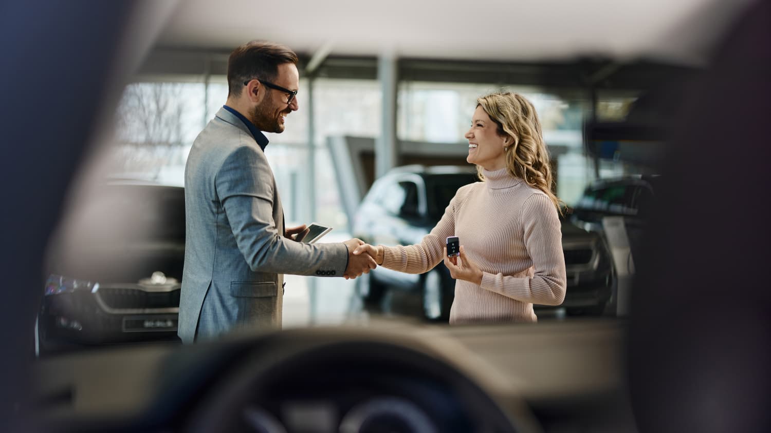 Ein Autoverkäufer schüttelt die Hand einer Kundin