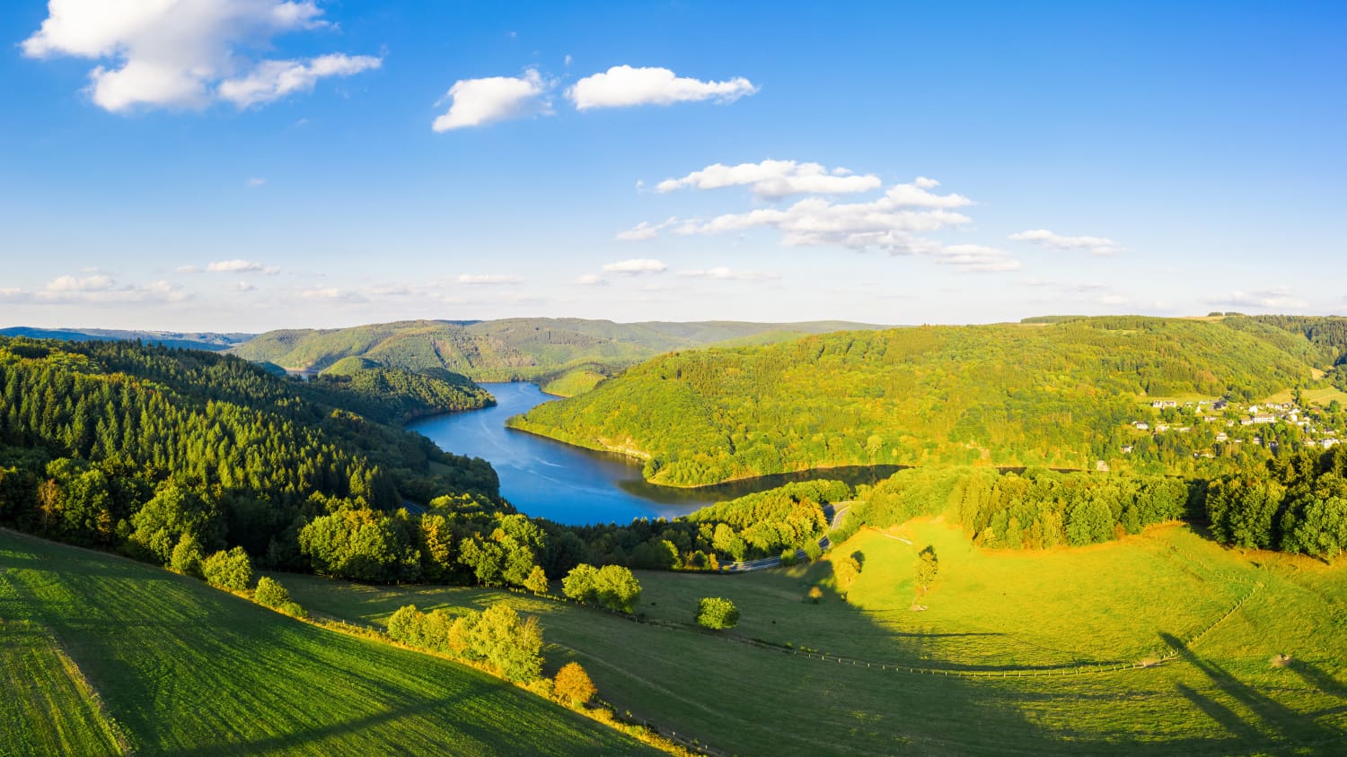 Weiter Blick über eine hügelige Landschaft mit See
