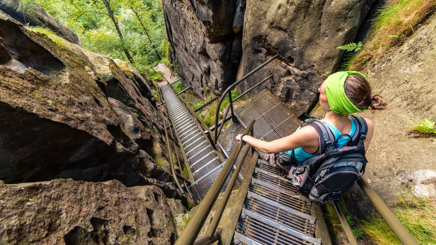 Frau geht eine steile Treppe in den Bergen hinunter