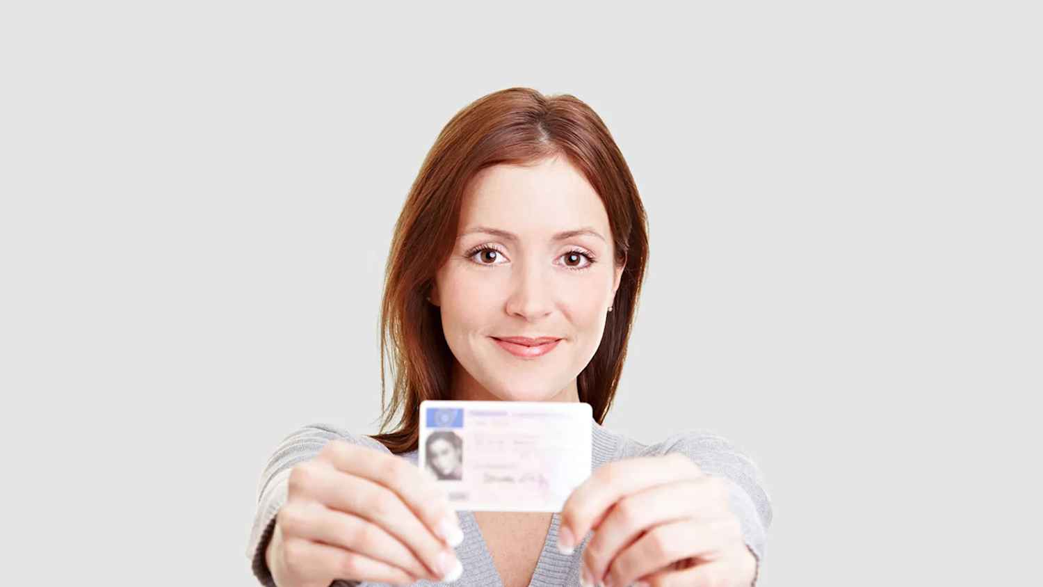 Eine Frau hält einen Führerschein in die Kamera