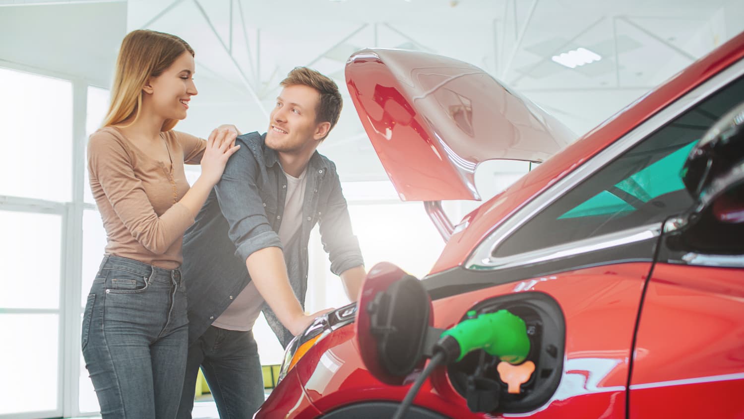 Junges Paar vor einem Elektroauto in einem Autohaus