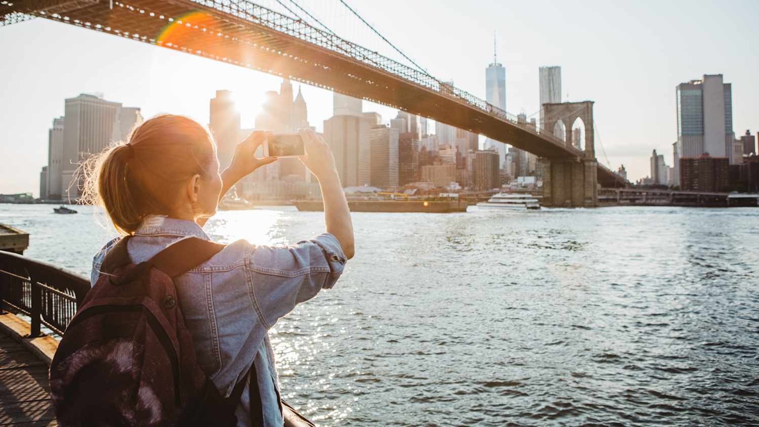 Eine Touristin steht vor der Skyline von New York und macht ein Foto