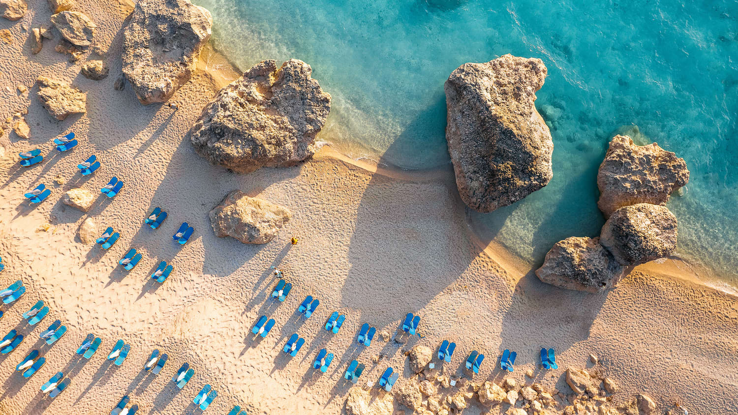 Luftaufnahme eines Strands mit Sonnenliegen in Griechenland