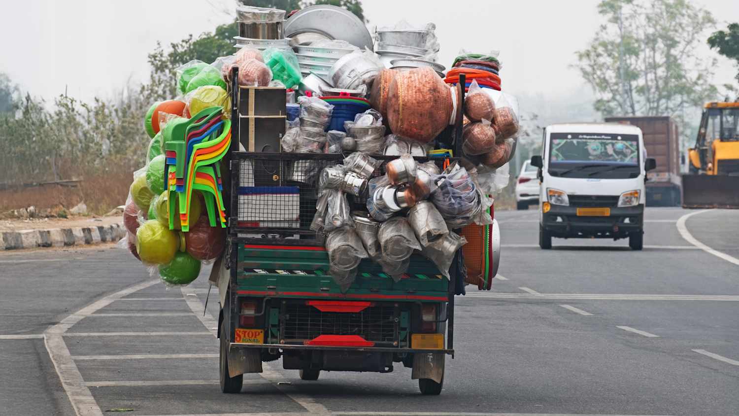 Ein überladenes Auto fährt auf einer Straße in Indien