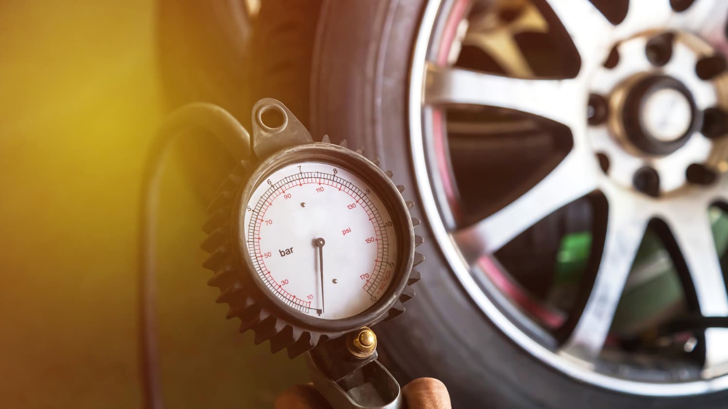 Mann prüft Luftdruck an einem Autoreifen