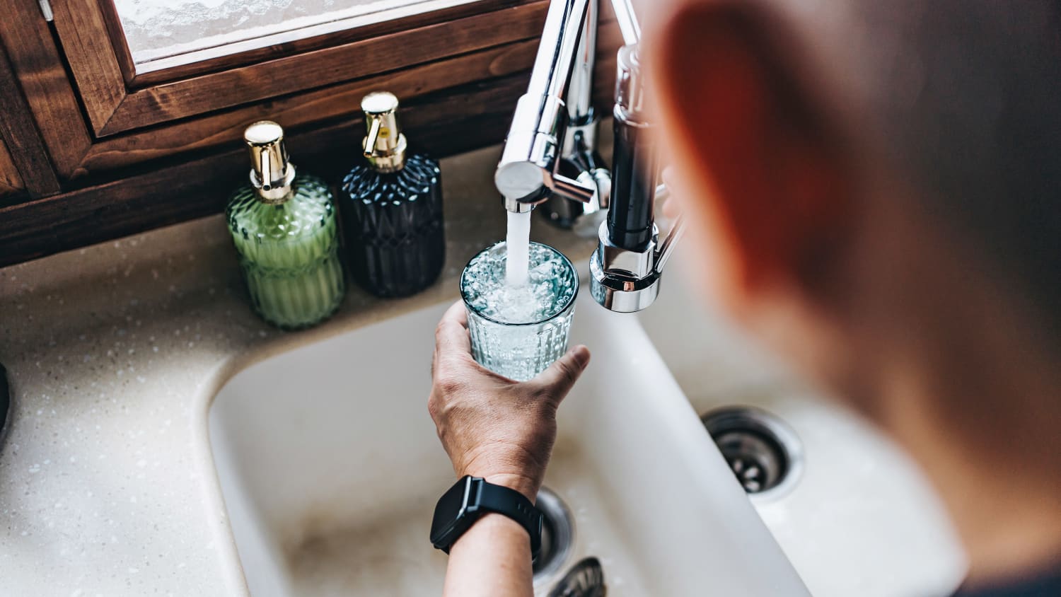 Ein Mann füllt sich Wasser aus dem Wasserhahn in ein Glas