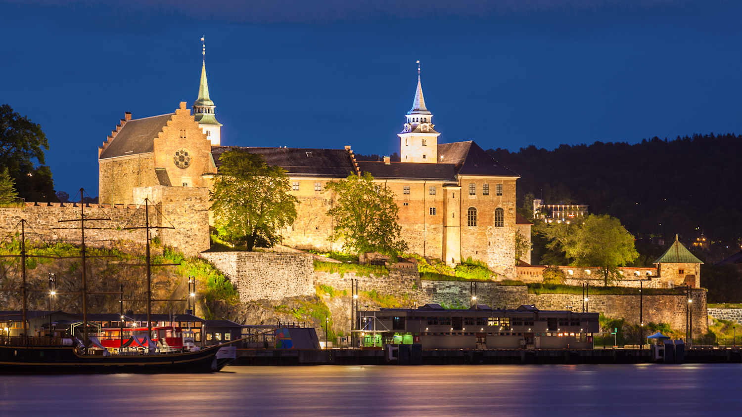 Außenansicht der beleuchteten Festung Akershus bei Nacht