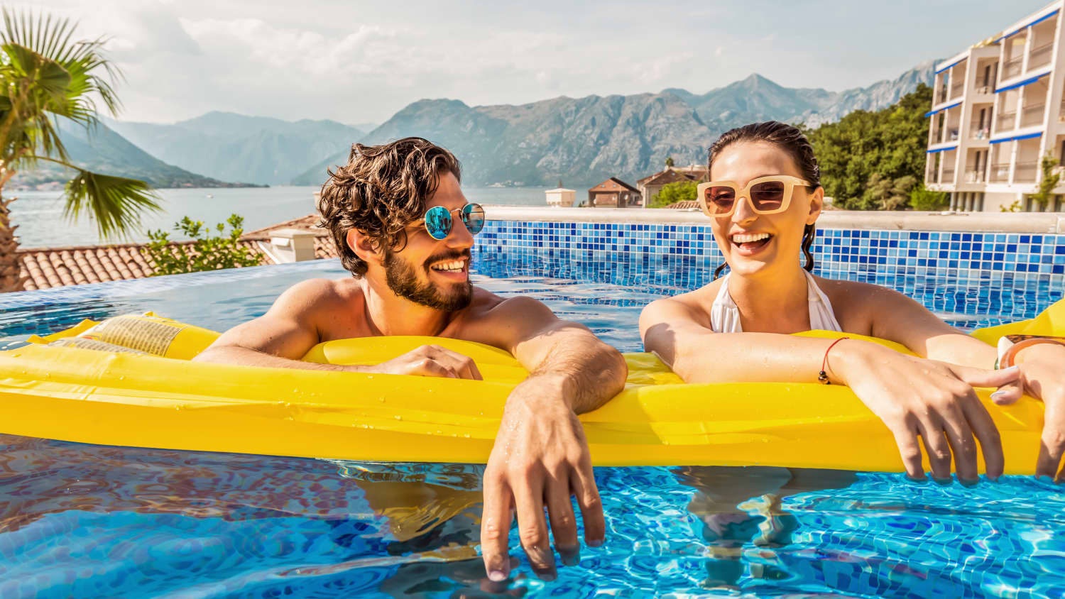 Ein Paar lehnt sich auf eine Luftmatratze im Hotelpool