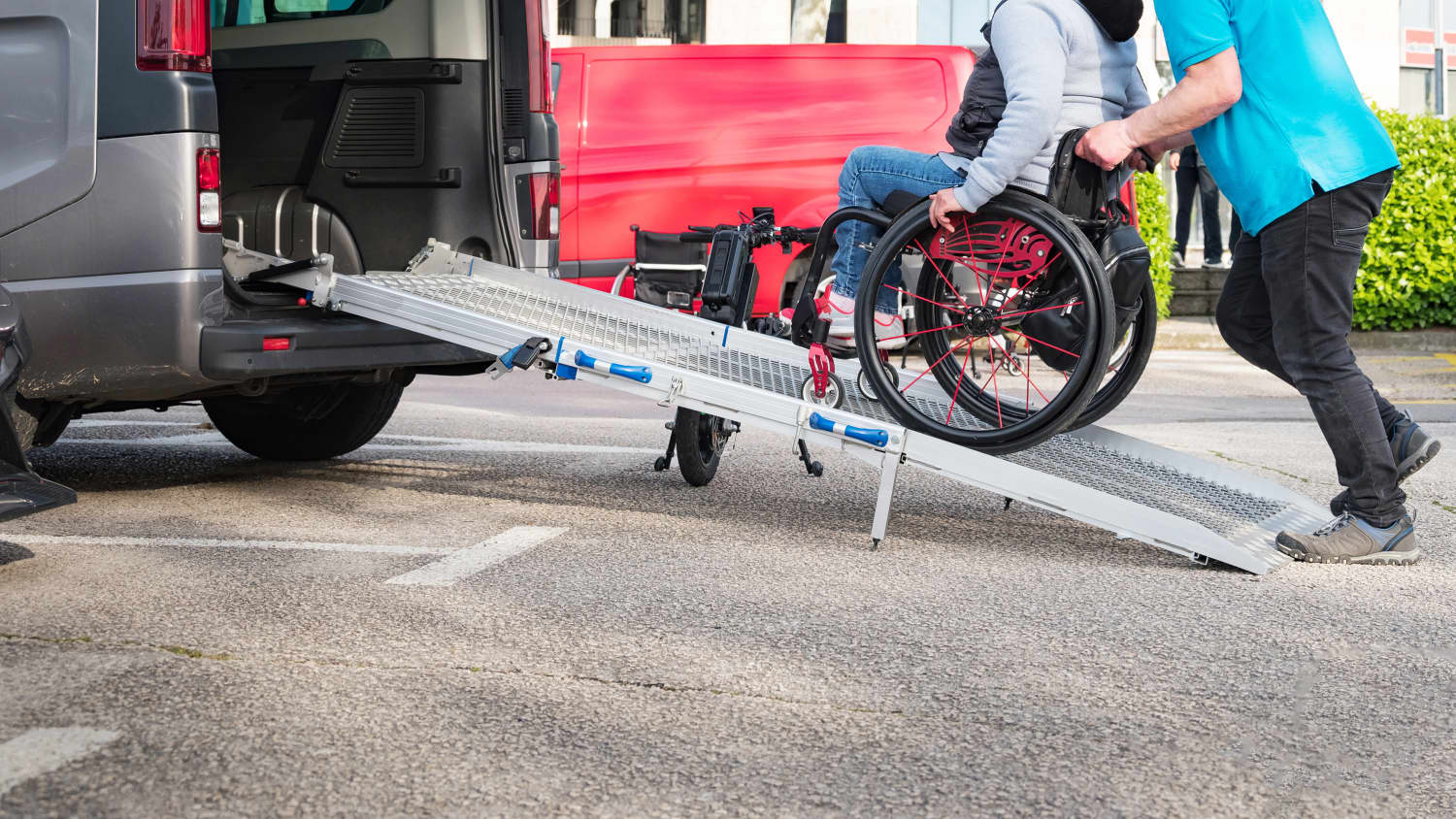 Ein Rollstuhlfahrer der Mittels einer Rollstuhlrampe in ein Auto geschoben wird
