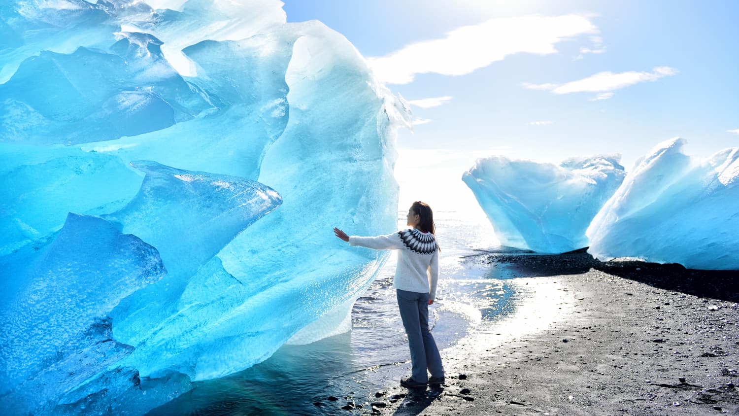 Frau steht an Eisberg in Island