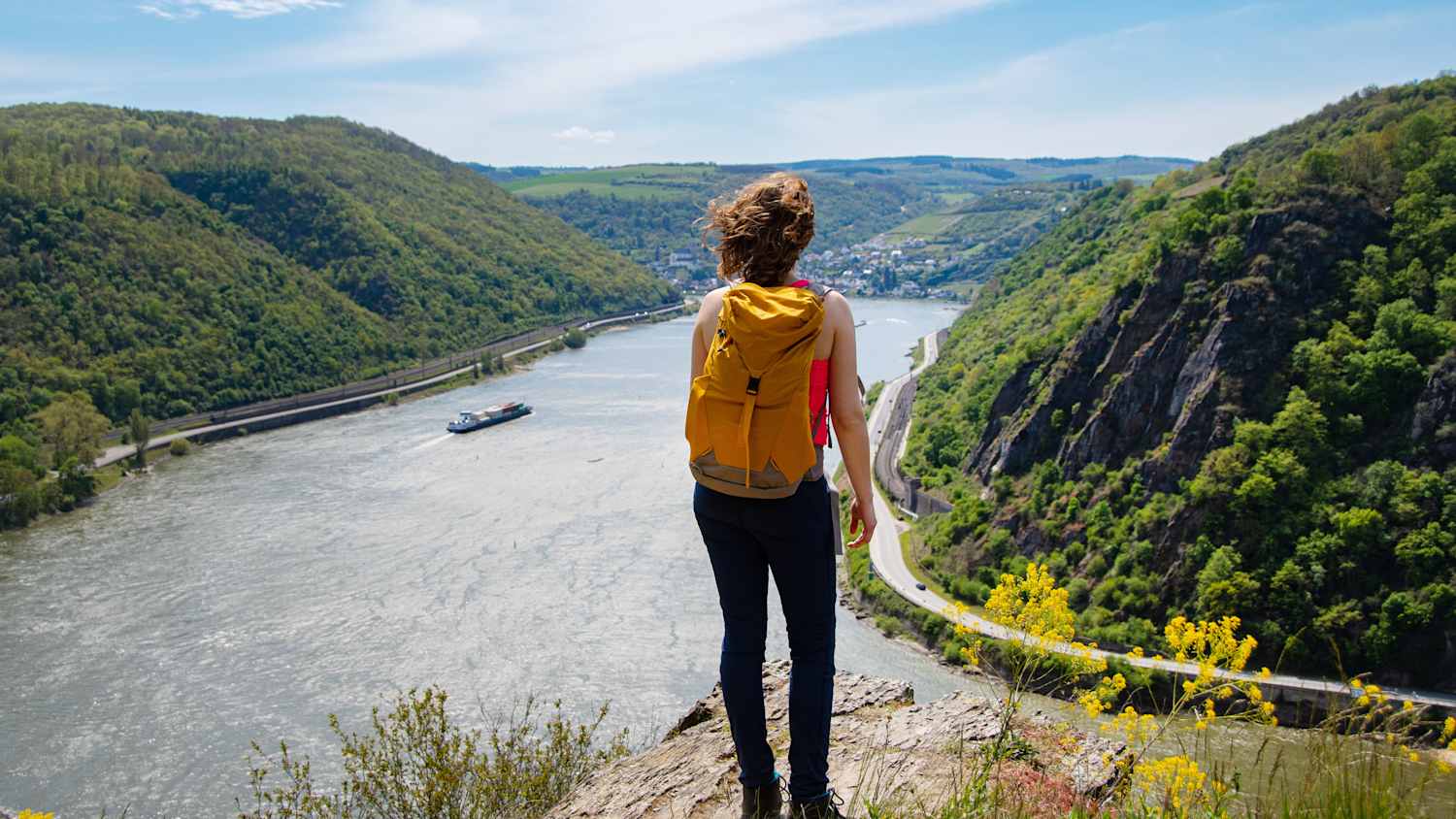 Eine Frau blickt bei ihrer Wanderung auf den Rhein
