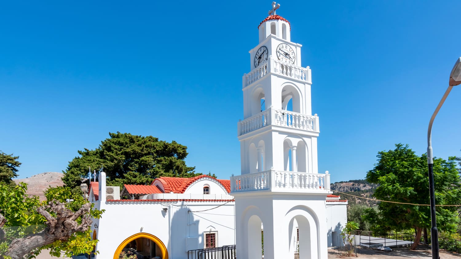 Das weiße Kloster Tsambika mit seinem offenem Turm vor blauem Himmel auf Rhodos, Griechenland
