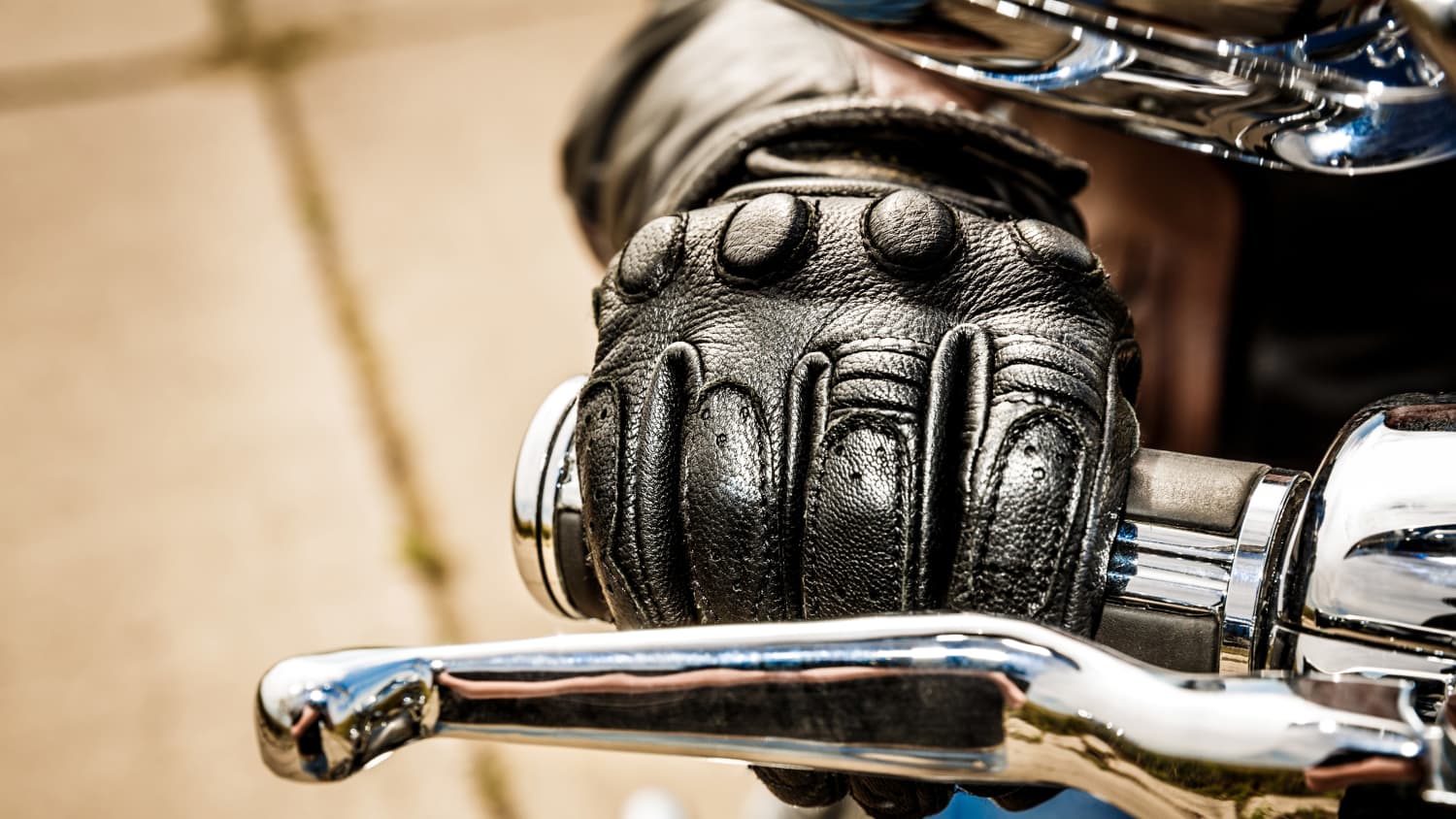 Ein Motorradfahrer mit Motorradhandschuh am Lenker