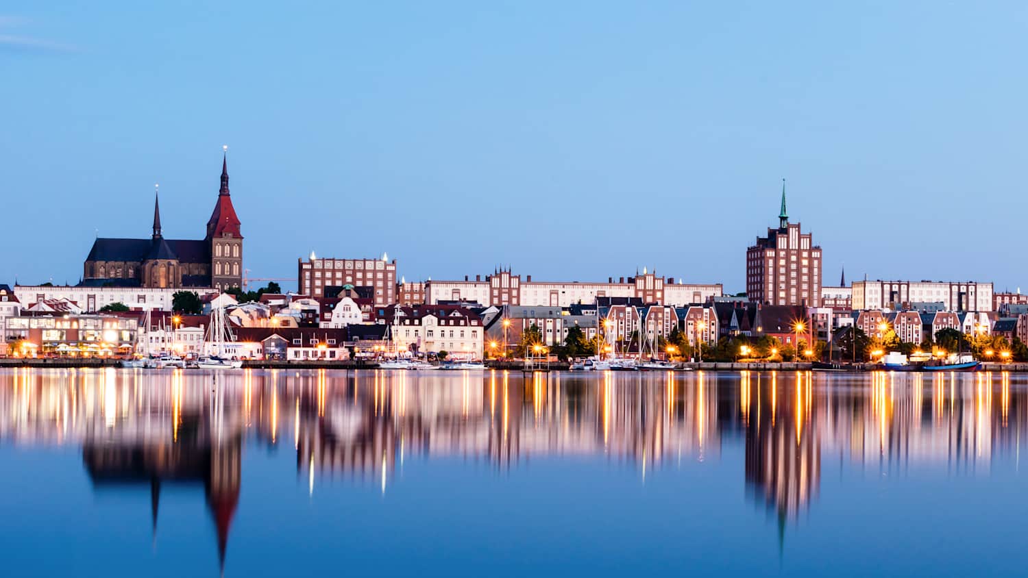 Blick auf die beleuchtete Stadt Rostock bei Abenddämmerung