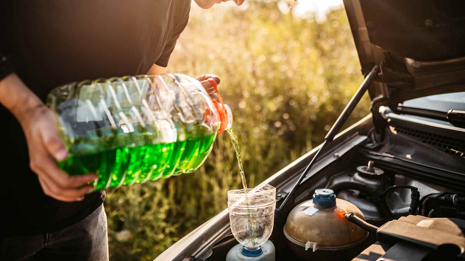 Ein mann der im Frühling Scheibenwischwasser für das Auto nachfüllt