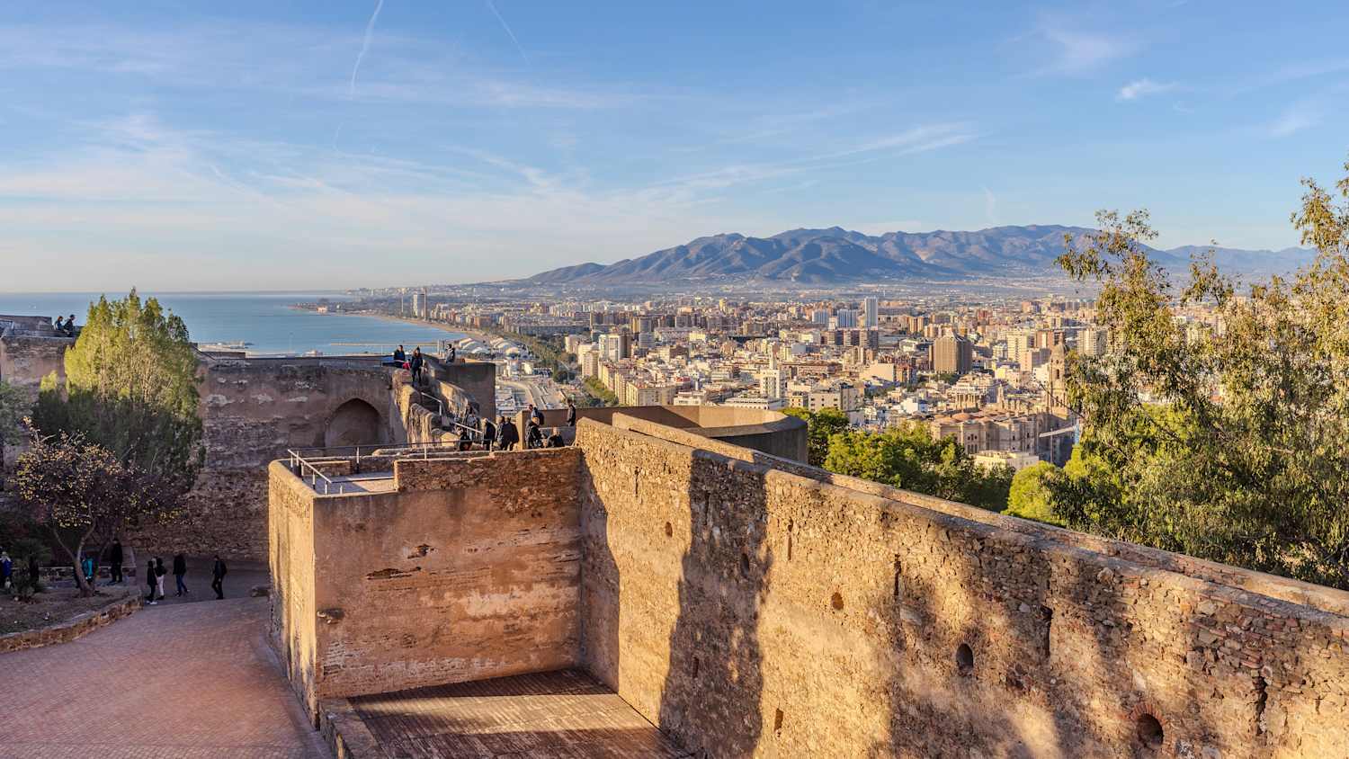 Ein wunderschöner Blick auf die Stadtlandschaft von Malaga mit ein paar Besuchern auf der Burg Gibralfaro im Vordergrund.