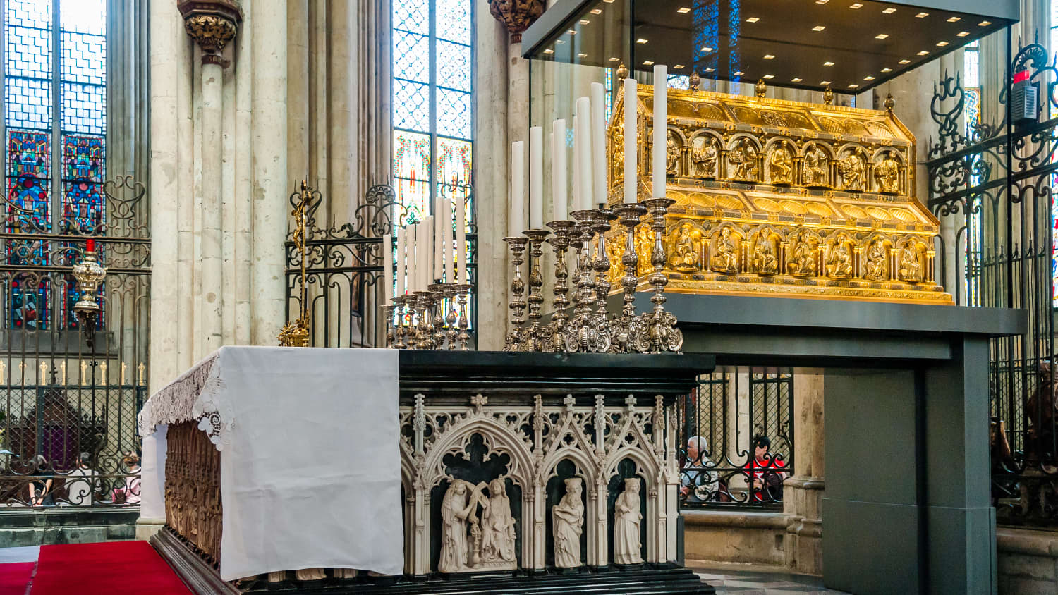 Der Dreikönigsschrein im Kölner Dom in einem großen Glaskasten mit Kerzen davor