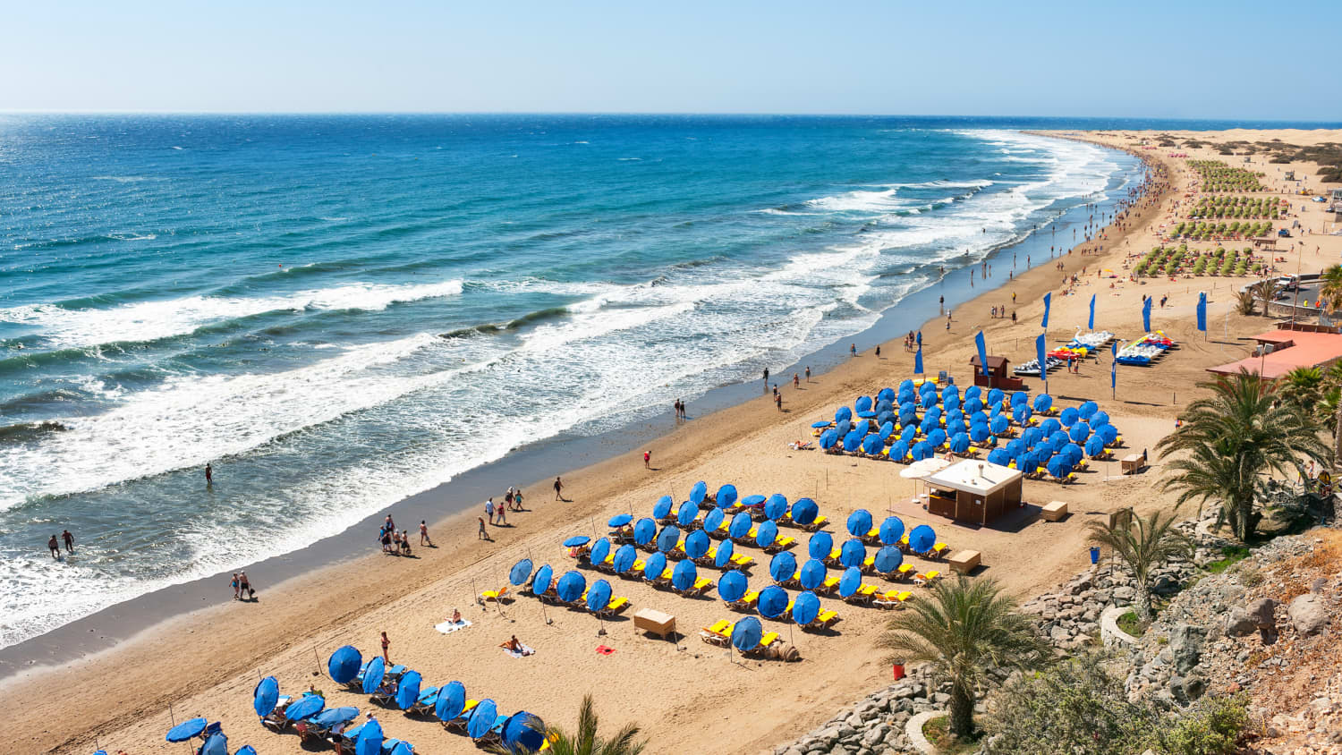 Der lange Sandstrand Playa del Inglés, nahe Maspalomas auf Gran Canaria mit blauen Sonnenschirmen