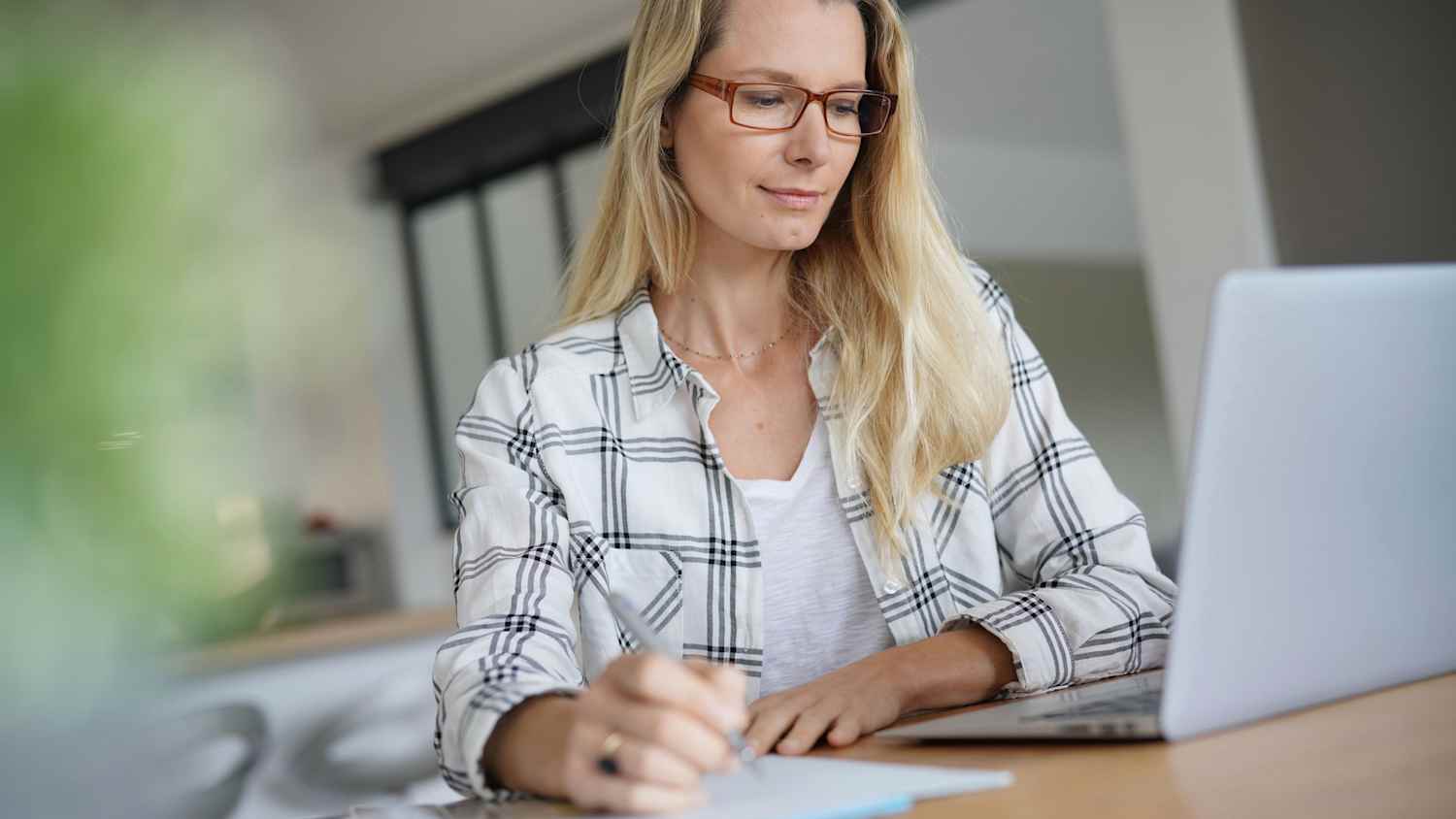 Eine Frau sitzt am Tisch und schreibt einen Brief