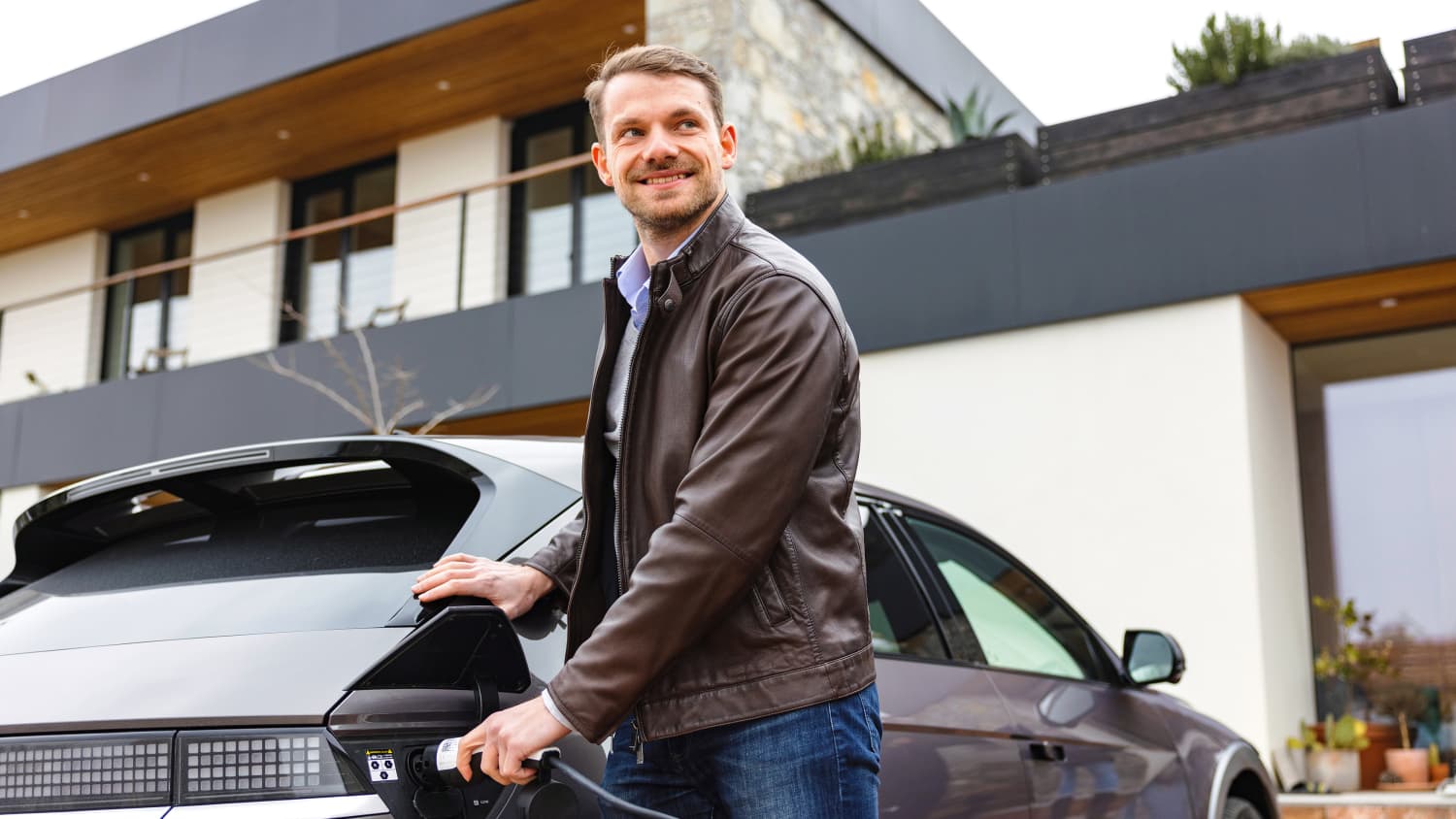 Ein Mann lädt sein Elektroauto vor dem Haus