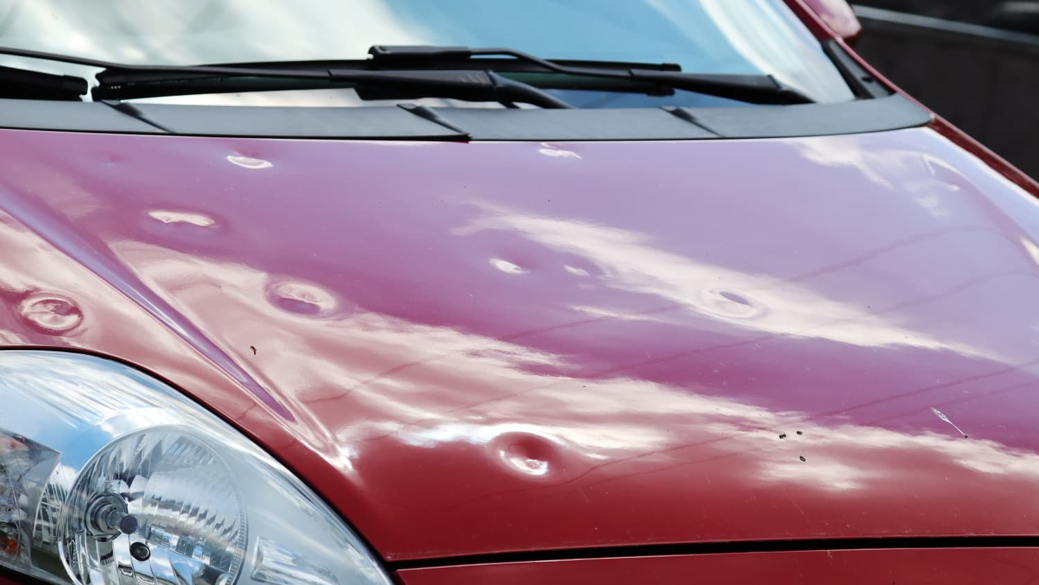 Eine Motorhaube hat deutliche Dellen nach einem Hagelsturm