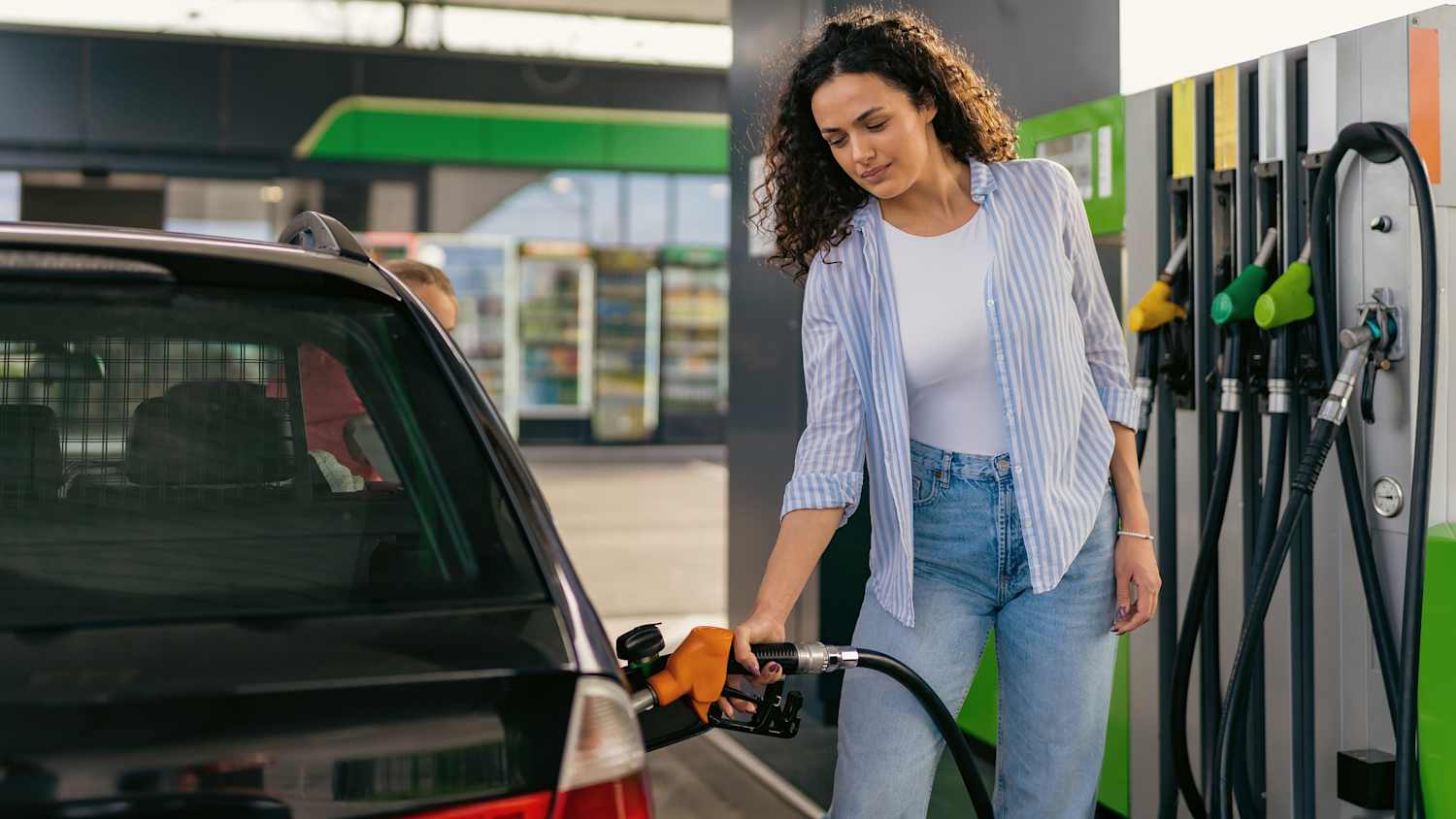 Eine Frau betankt ihr auto an einer Tankstelle mit Benzin