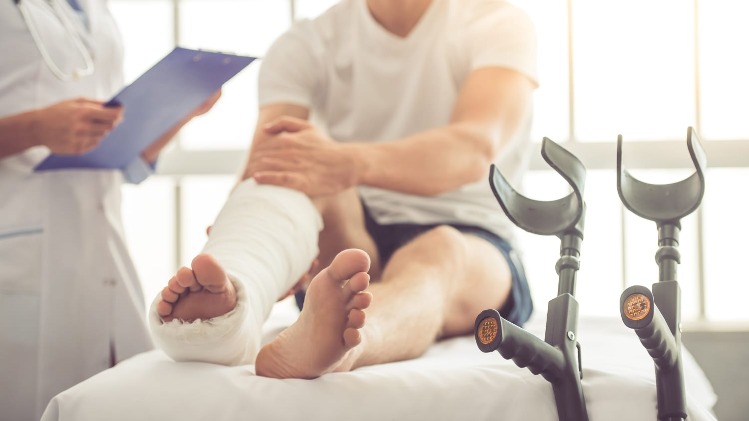 Ein Patient wird beim Arzt mit einem Gipsbein behandelt