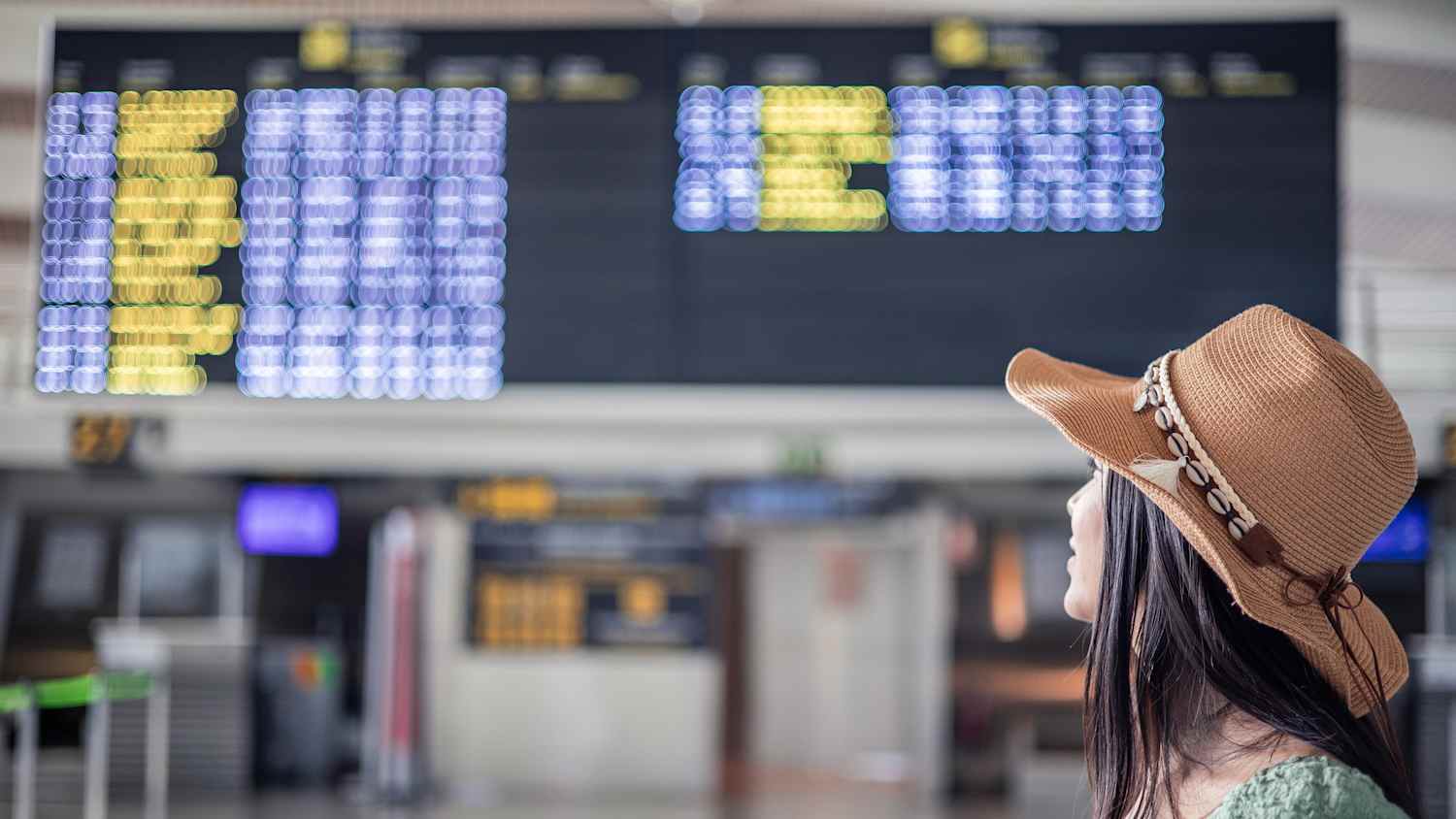 Eine Frau schaut auf die Abflugtafel am Flughafen