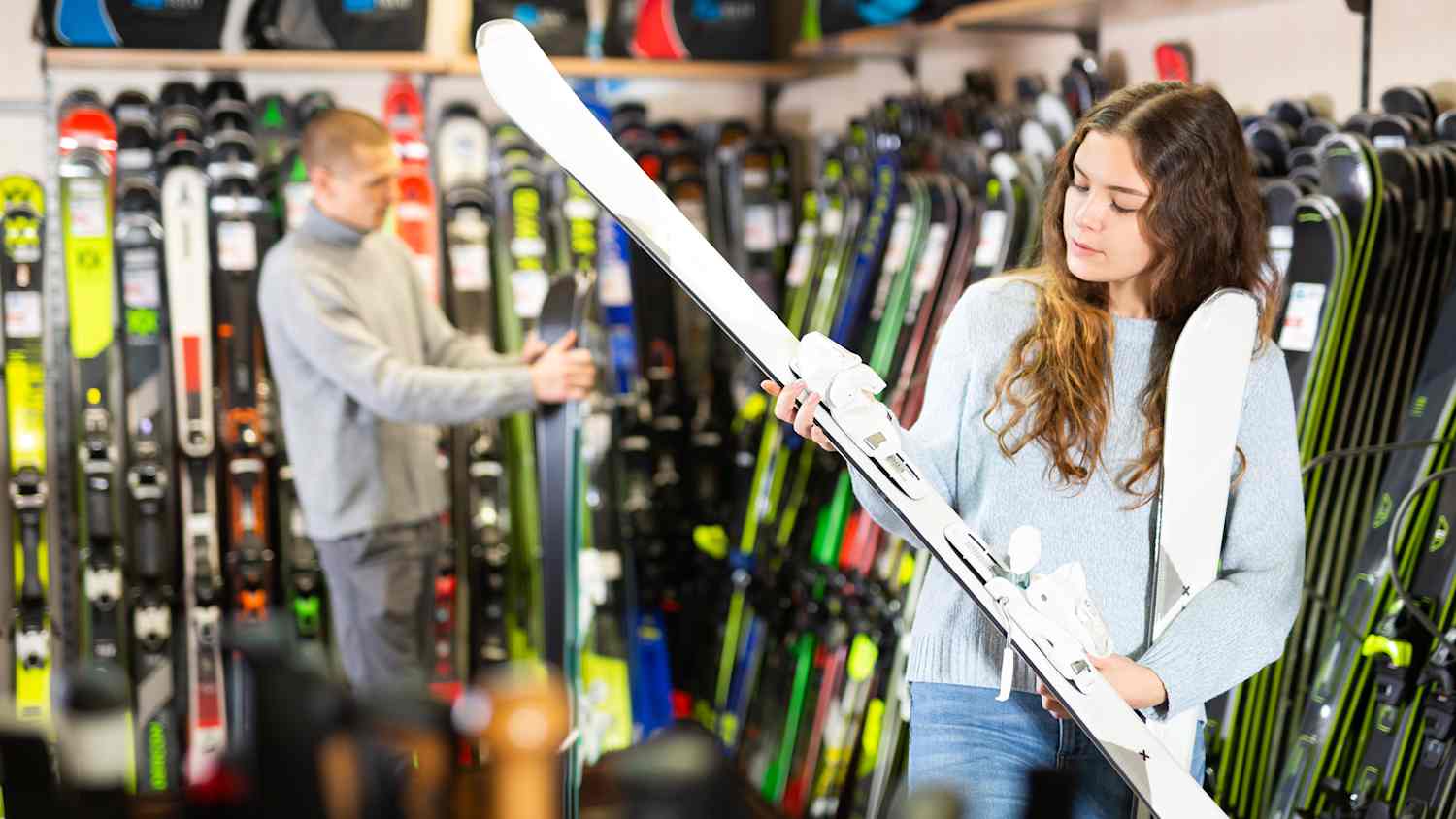 Eine junge Frau sieht sich Ski in einem Skiverleih an
