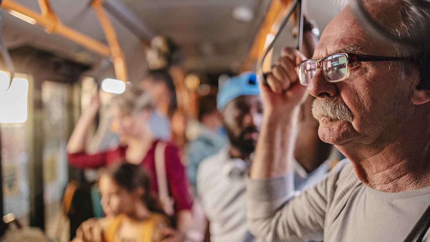 Ein älterer Mann hält sich im Bus fest