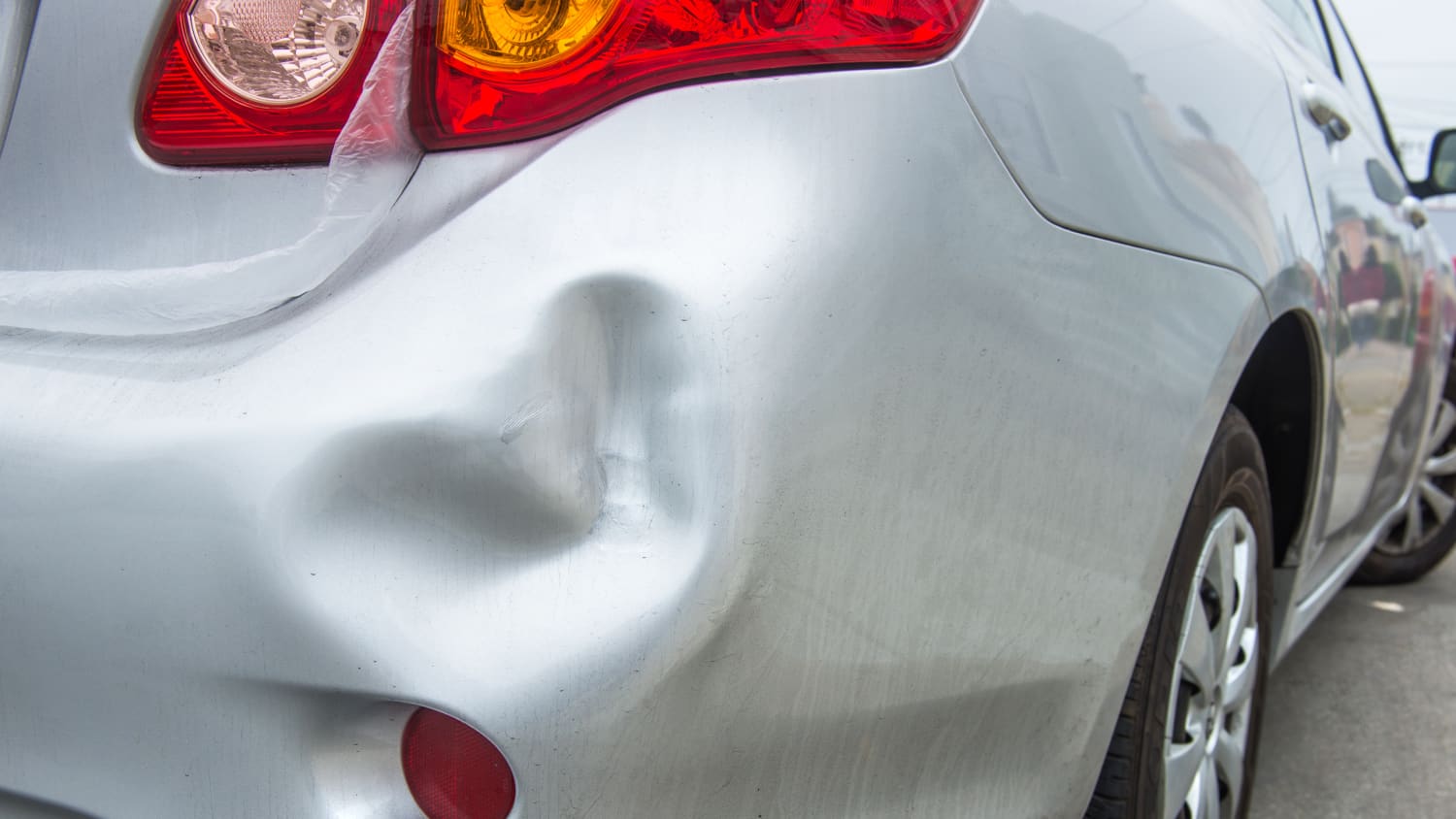Silbernes Auto mit großer Delle im Kofferraum