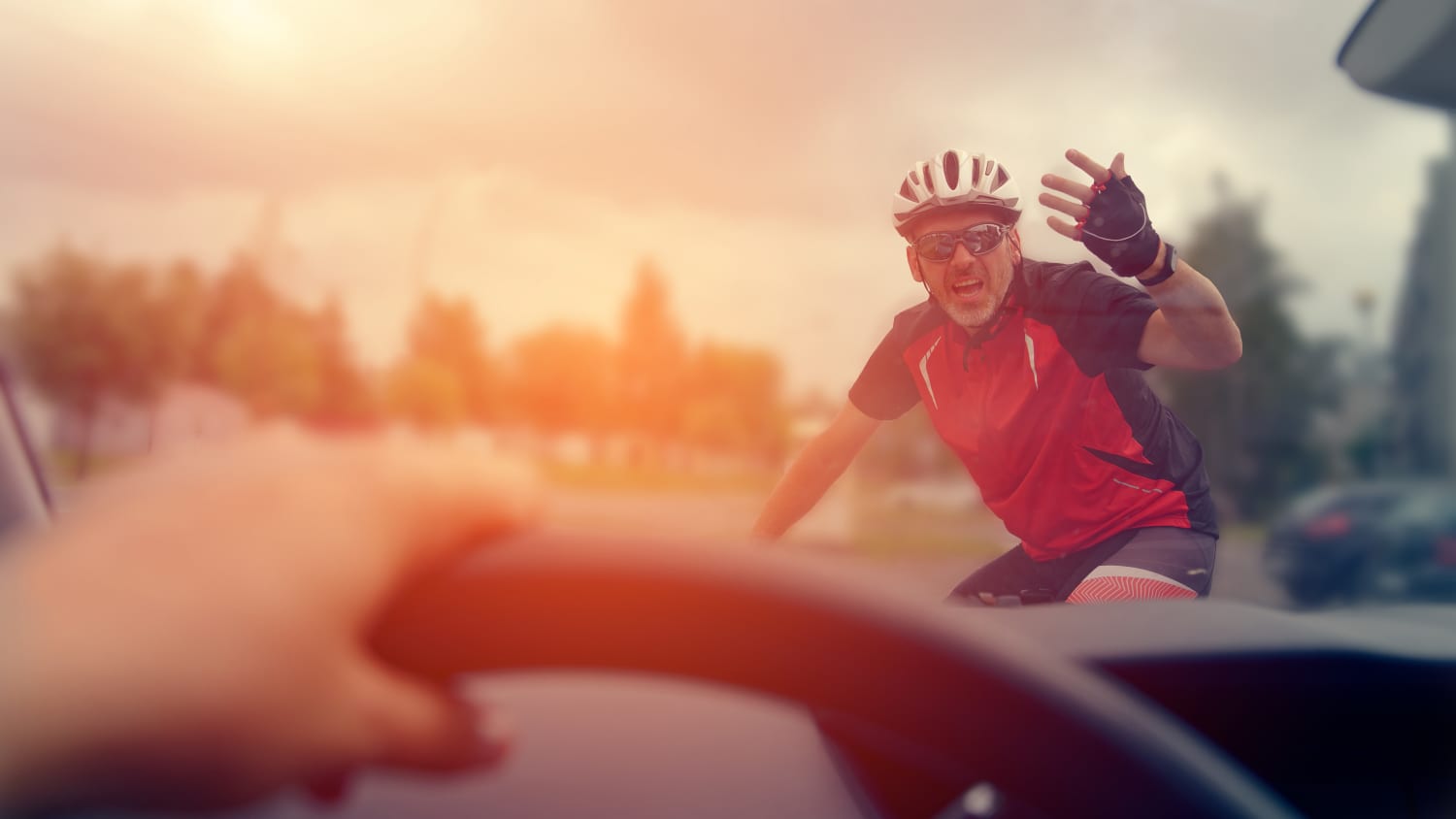 Ein verärgerter Radfahrer gestikuliert einem Autofahrer zu