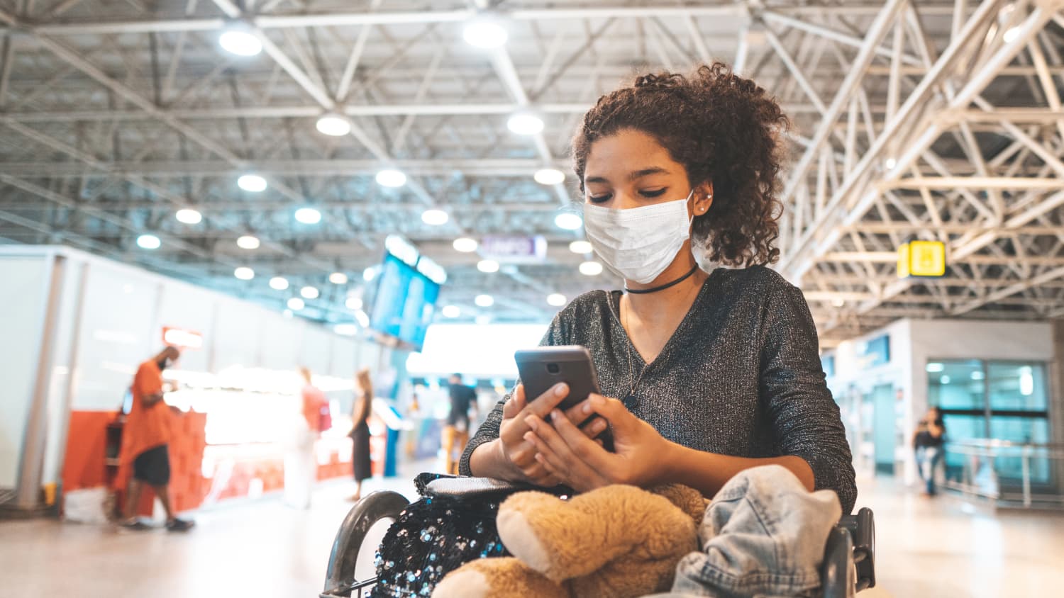 Junge Frau schaut an einem brasilianischen Flughafen auf ihr Handy