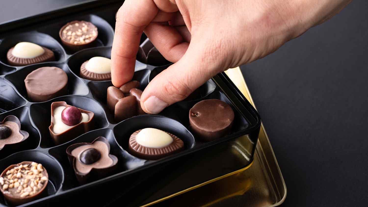 Ein Mann nimmt eine Praline aus einer Pralinenschachtel