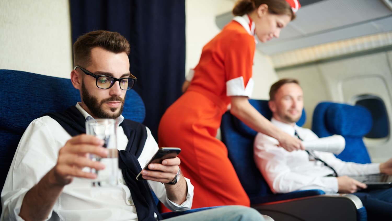 Fluggast arbeitet am Handy auf seinem Sitzplatz in der Businessclass