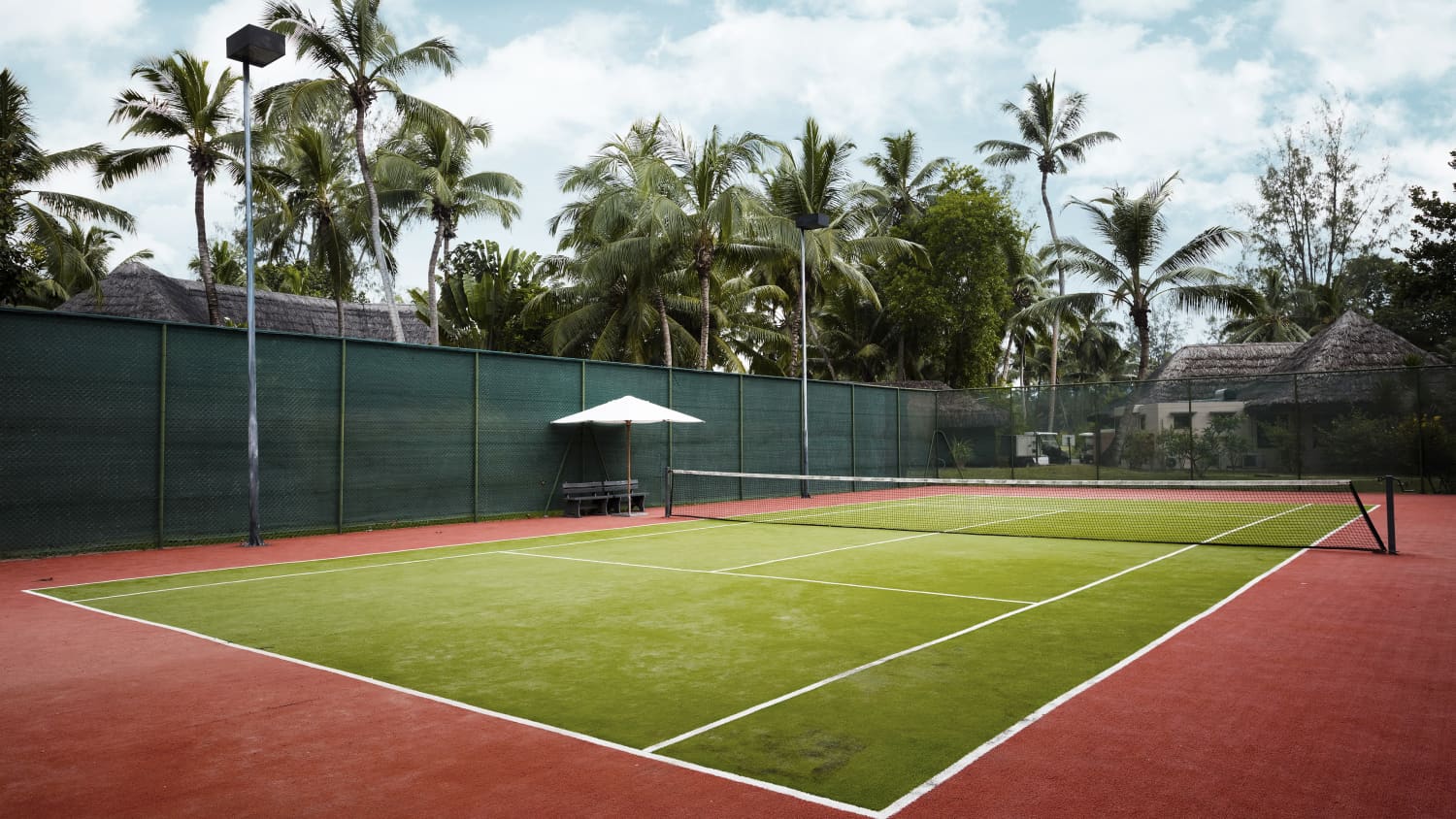 Blick auf einen Tennisplatz mit Palmen im Hintergrund.