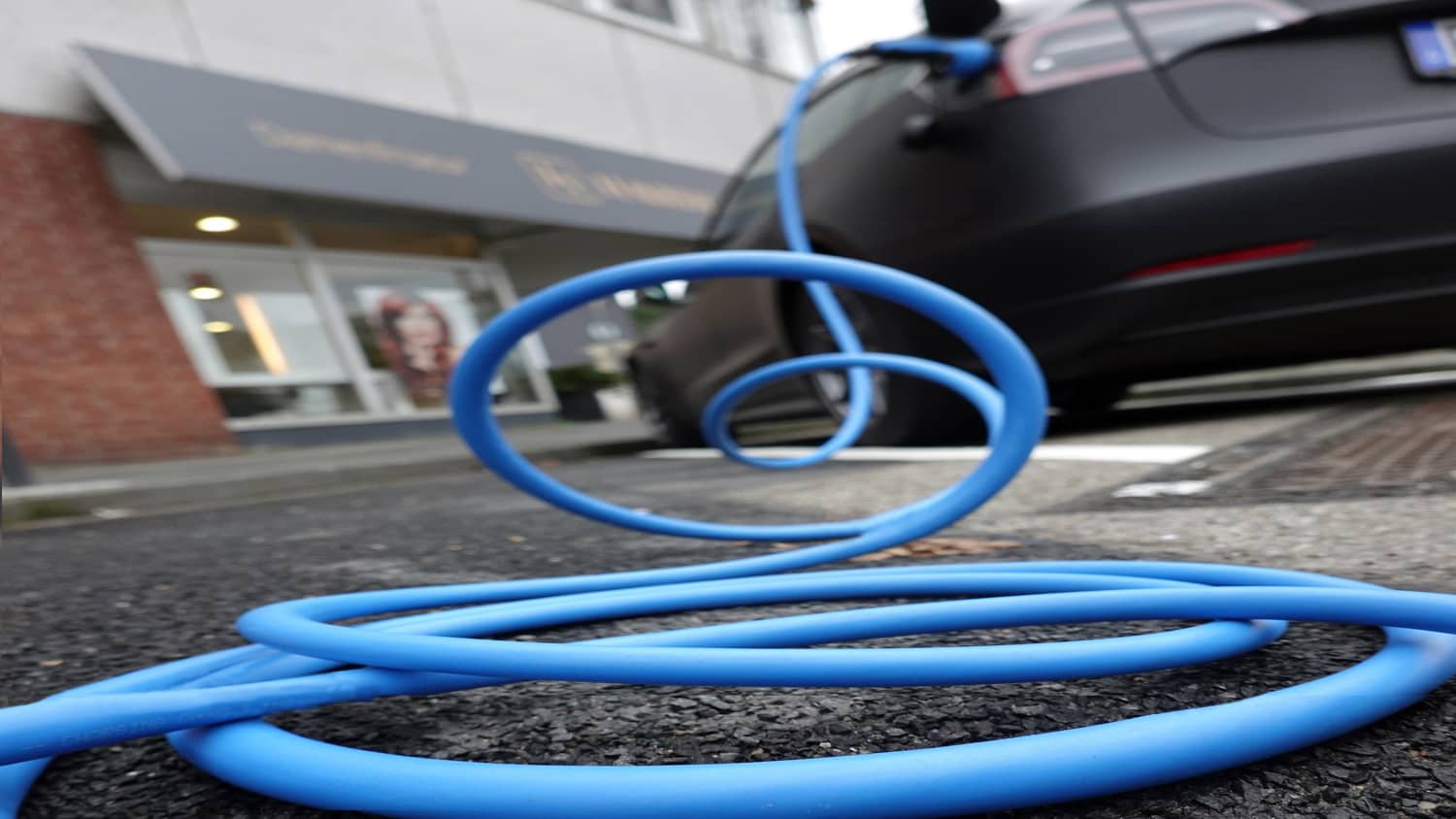 Ein Ladekabel für ein e-Auto liegt auf dem Gehweg