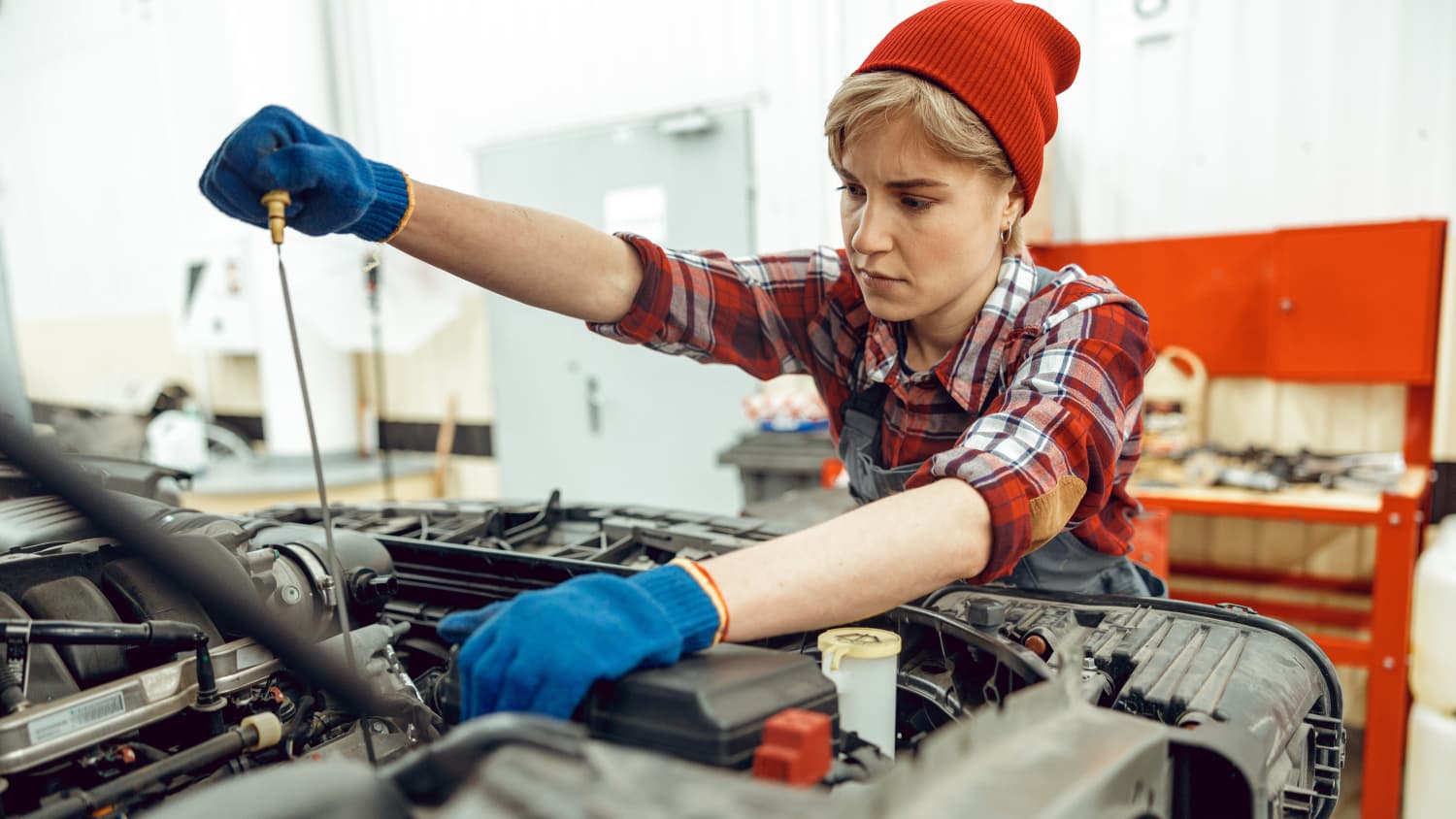 Eine Mechanikerin prüft den Ölstand in einem Auto