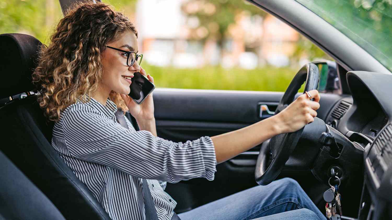 Eine Frau telefoniert mit ihrem Handy am Steuer ihres Autos